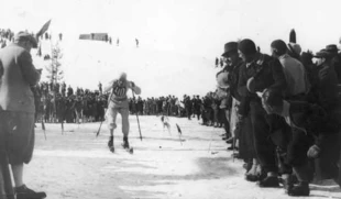 Bronisław Czech na trasie biegu narciarskiego, publiczność blisko zawodnika, bez odgradzającego pasa reklam. Międzynarodowe Zawody Narciarskie o Mistrzostwo Polski w Zakopanem, luty 1934 r. Bronisław Czech był najwszechstronniejszym polskim narciarzem okresu międzywojennego, trzykrotny olimpijczyk, taternik, ratownik górski, instruktor narciarski, pilot i instruktor szybowcowy, patriota, zmarł w Auschwitz-Birkenau w 1944 r. Fot. Narodowe Archiwum Cyfrowe