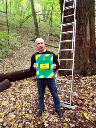 Dyrektor Kijowskiego Centrum Ekologiczno-Kulturalnego Wołodymyr Borejko z tablicą urzędową botanicznego pomnika przyrody przed dębem Grigorija Kożewnikowa. Fot. Iwan Parnikoza