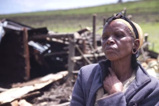 Kobieta z plemienia Ogiek Elisabeth Tabinoy siedzi przed pozostałościami swojego podpalonego i zniszczonego domu. Ngongeri, Njoro, Kenia. Fot. Lewis Davis © Survival International